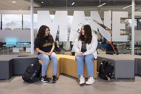 Two students sit on a couch outside of the PNW Mane Zone.