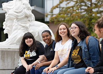 Five students sit on a bench outside of the Nils Bioscience Building.
