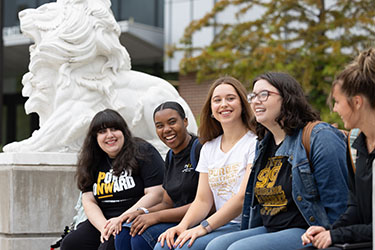Five students sit on a bench outside of the Nils Bioscience Building.