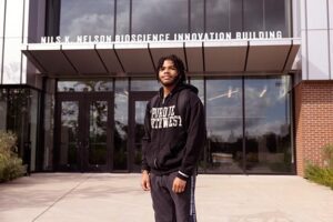A PNW student stands in front of the Nils K. Nelson Bioscience Innovation Building.