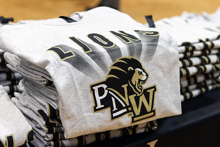 A PNW Lions t-shirt opened up on a pile of shirts