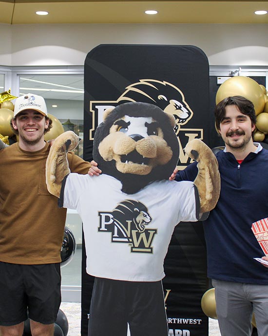 PNW students pose with a cardboard cutout of PNW mascot Leo the Lion.