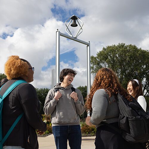 Students stand in front of the PNW Bell Tower