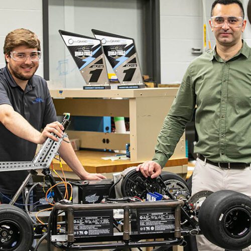 Andrew Miloshoff, standing on the left, and Khair Al Shamaileh work on an evGrand Prix vehicle.