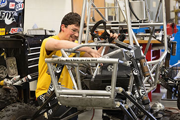 An engineering student adjusts a racer.