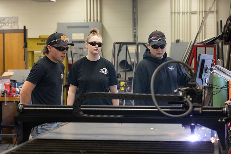 Students on the Baja motorsports team watch a machine