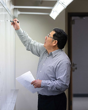 Professor Zhang writes on a white board.