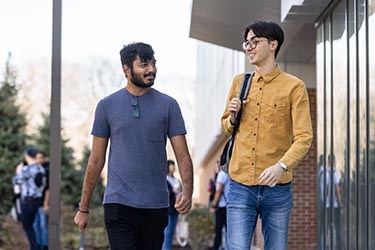 Two students walking next to each other outside of the NILS building