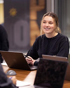 A PNW student works on a laptop at a conference table