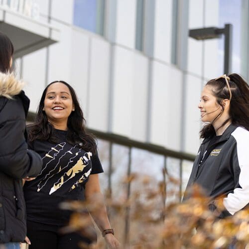 Three students stand together outside of the Nils K. Nelson Bioscience building