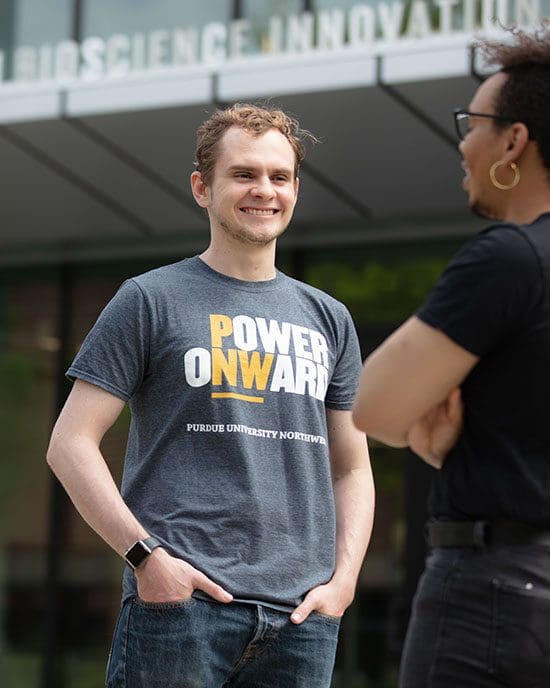 Two students stand outside and talk