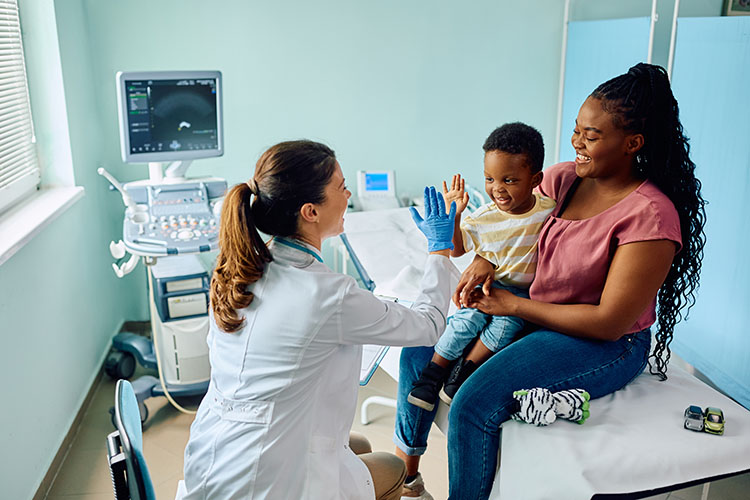 Happy child giving high five to his pediatrician after medical examination at doctor's office.