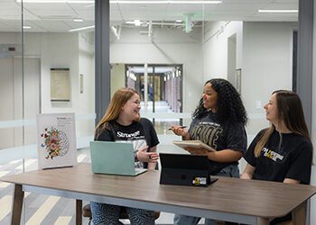 Three psychology students sit at a table.