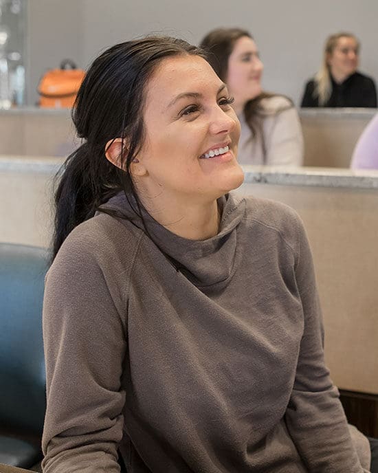 A smiling student sits at a desk.