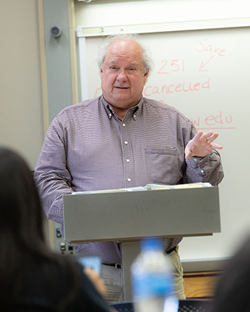 A professor stands at a podium while teaching.