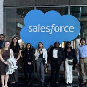 Diverse group of eight students in front of Salesforce sign