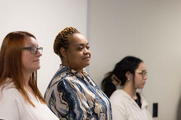Three PNW students standing while looking at the professor 363x242