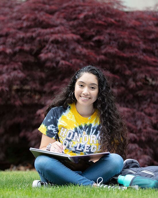 Student sitting outside with a notebook