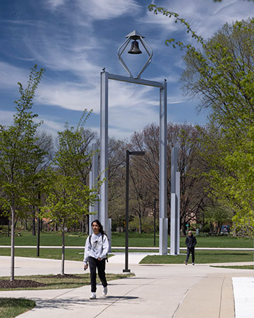 Students walk outdoors around the belltower on the Hammond campus