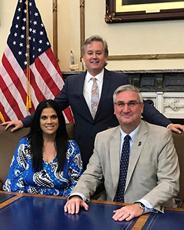 Nicky Jackson, Ralph Jackson and Governor Eric Holcomb posing at a desk