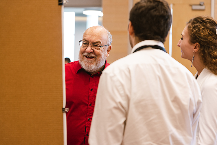 Jovial professor conversing with student researchers.