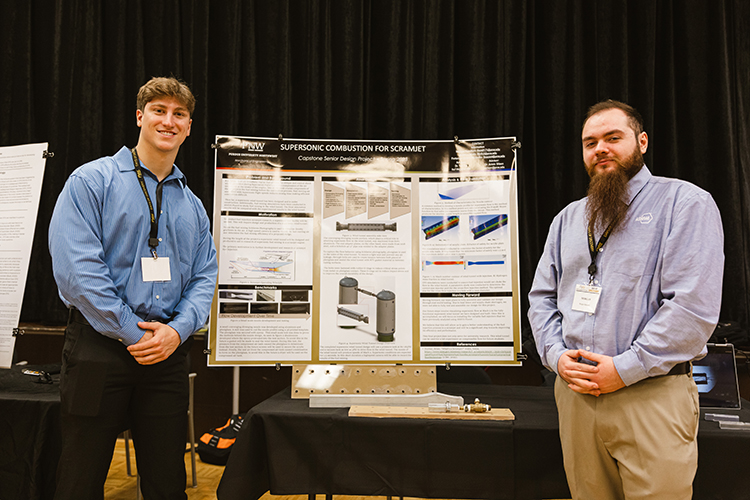 Two students flanking their research poster proudly.