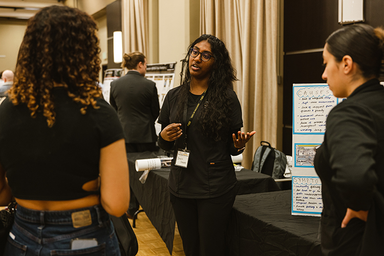 Student presenting research poster to students.