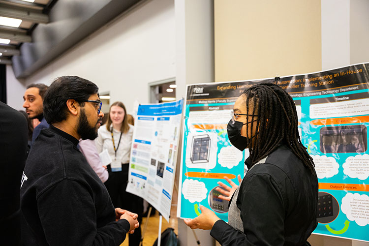Two people engaged in conversation at days of discovery, surrounded by displays and projects.