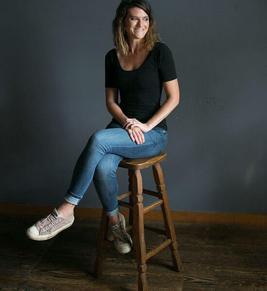 Lulu Miller sits on a wooden stool.