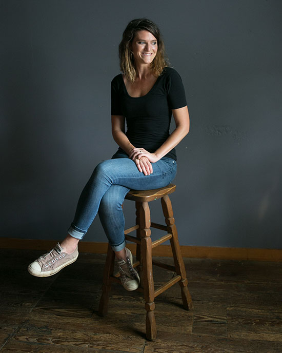 Lulu Miller sits on a wooden stool.