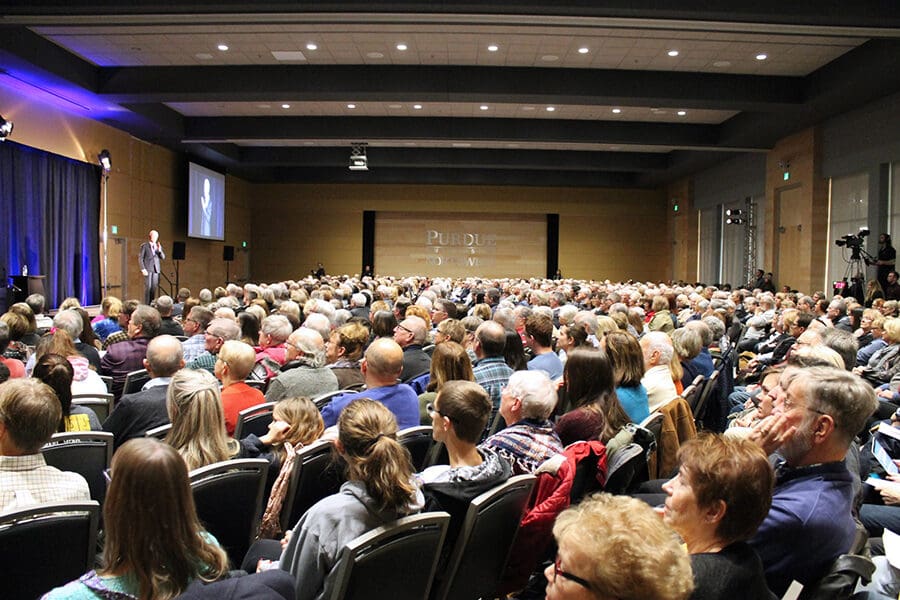 A crowd of people watch a speaker on stage