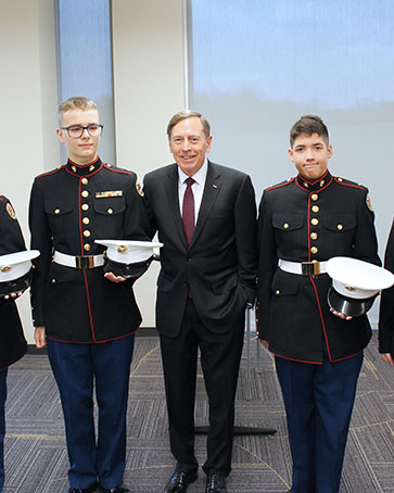 Students in Marine Corps JROTC uniforms pose with General David Petraeus