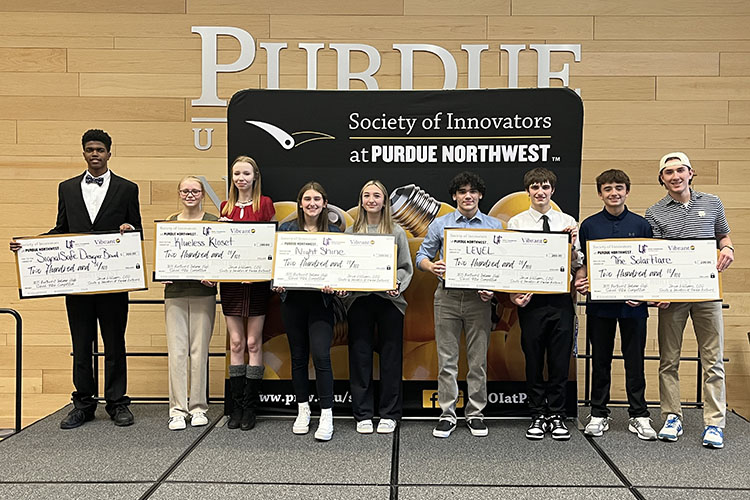 Nine students stand on stage as winners of the Society of Innovators High School Pitch Competition