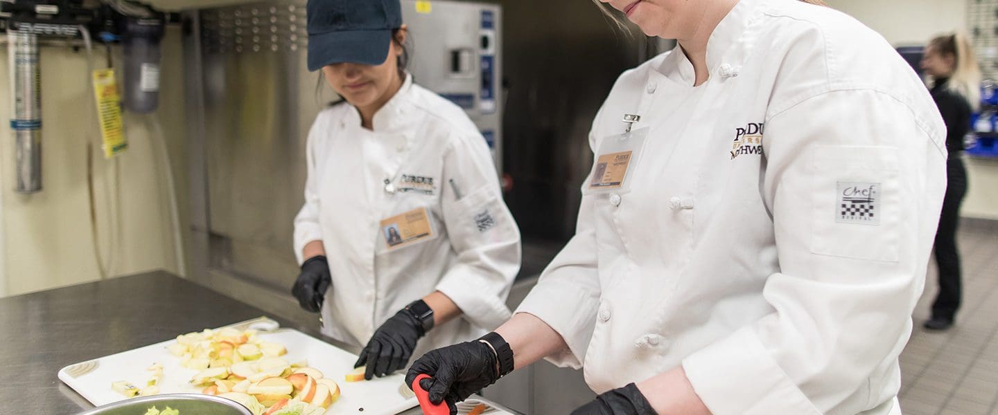 Two students chopping vegetables