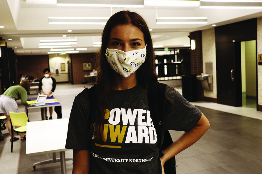 A PNW student in a mask poses inside SULB