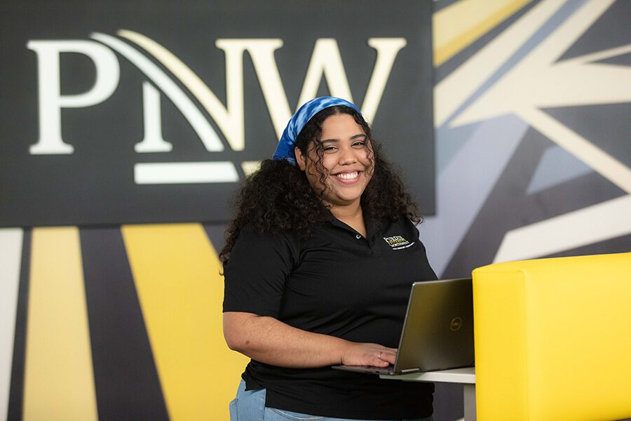 A student stands in front of a PNW sign.