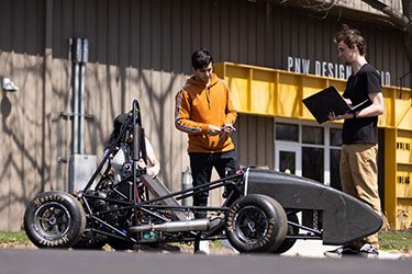 Engineering students work on a car.