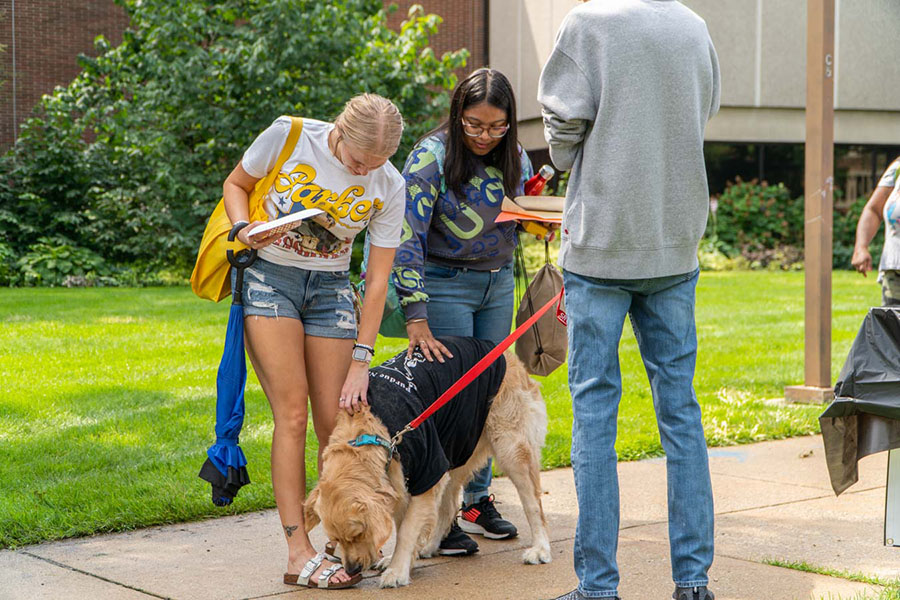 Students lean down to pet a dog