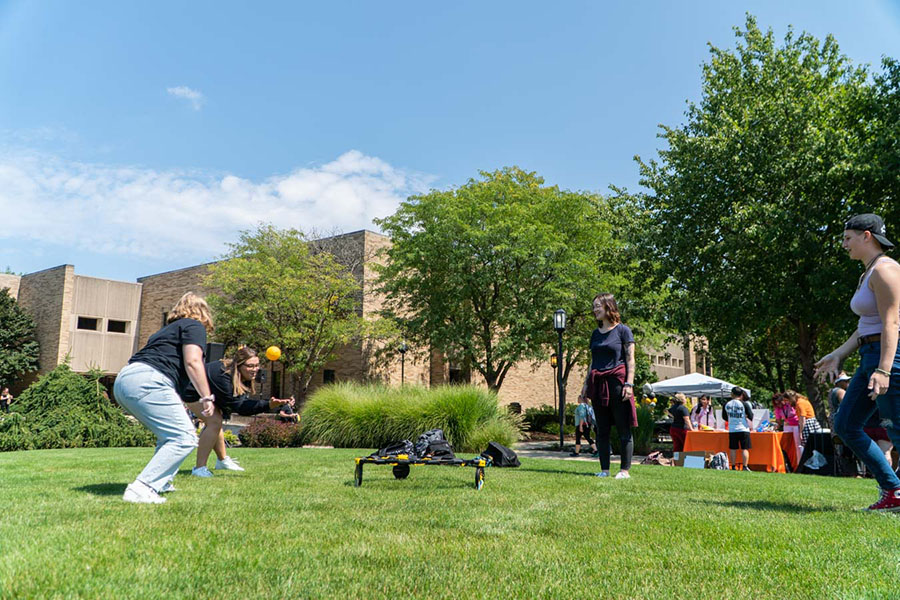 Students play spikeball in a grassy area