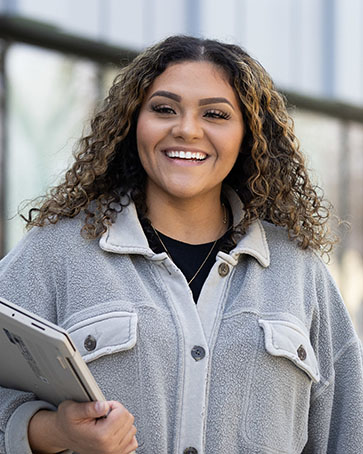 A PNW student holds books outdoors