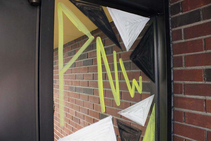 A window is painted to say "PNW" there are black, white, and gold triangles around the letters