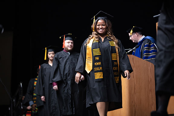 A graduate smiles as she crosses the stage.