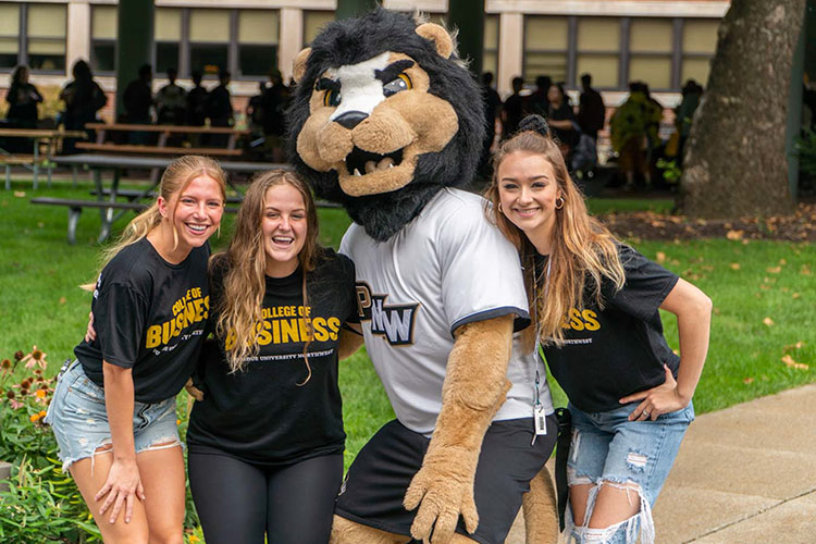 Three students pose with Leo, PNW's lion mascot