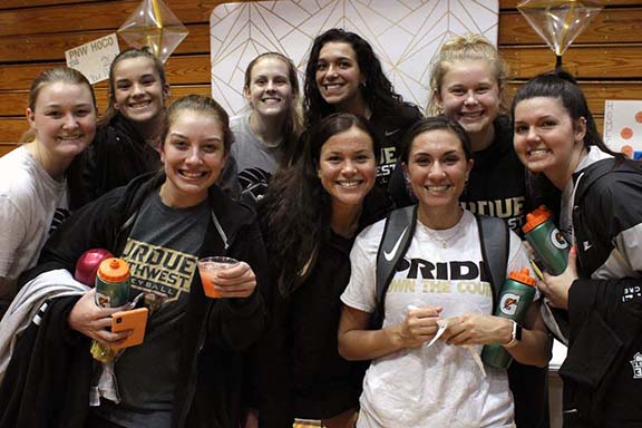 A group of student athletes pose in front of hand drawn homecoming signs