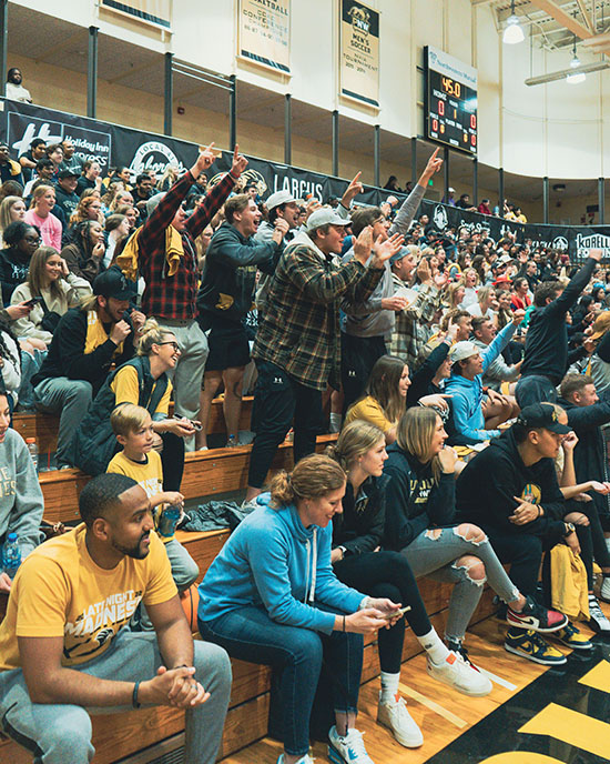 Students stand and sit in full bleachers