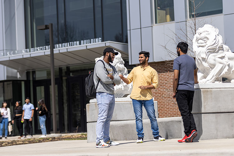 Three students stand outside the Bioscience and Innovation Building