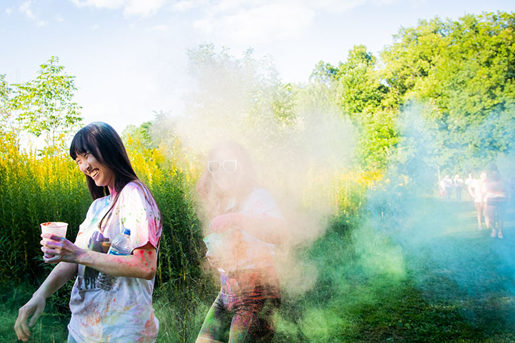 A student walks away from clouds of color powder