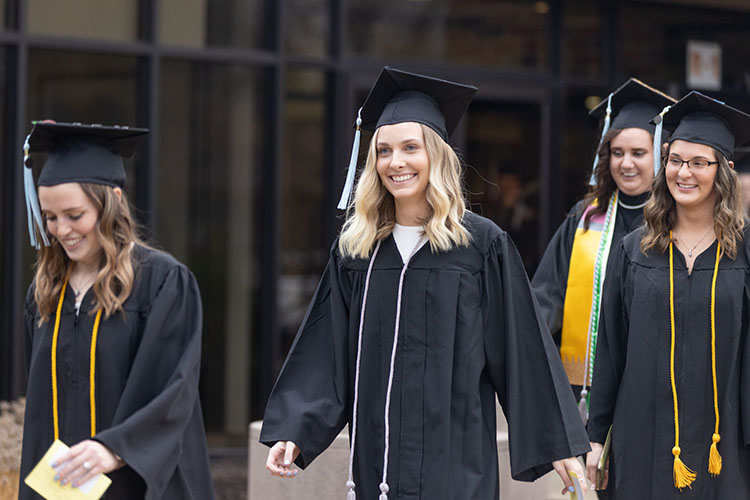 A first-generation PNW student showing off a silver cord at commencement