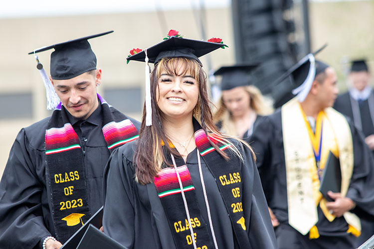 A first-generation PNW student showing off a silver cord at commencement