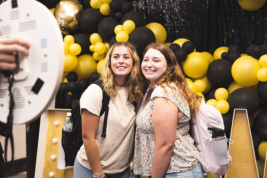 Two students pose together and smile